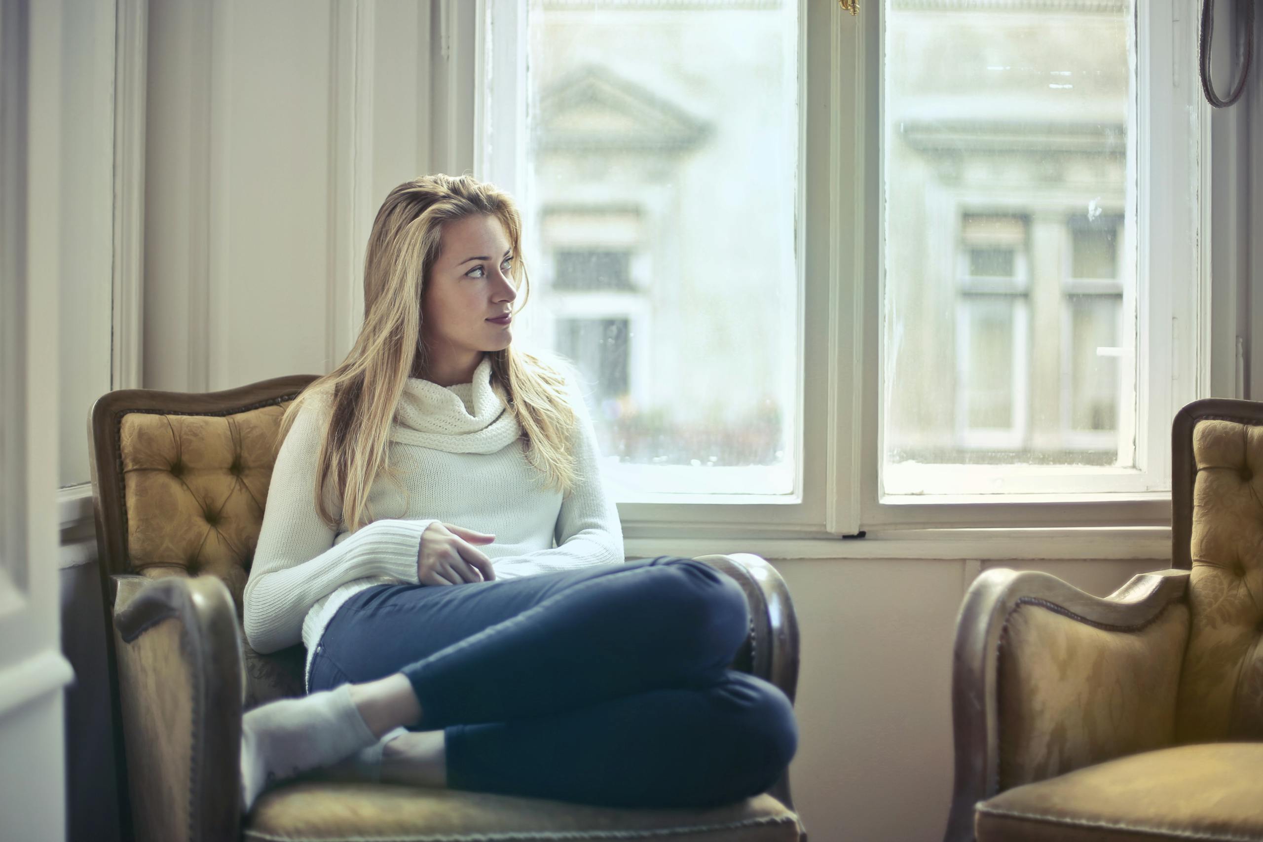 A serene moment of a woman in a cozy room, enjoying leisure time by the window.