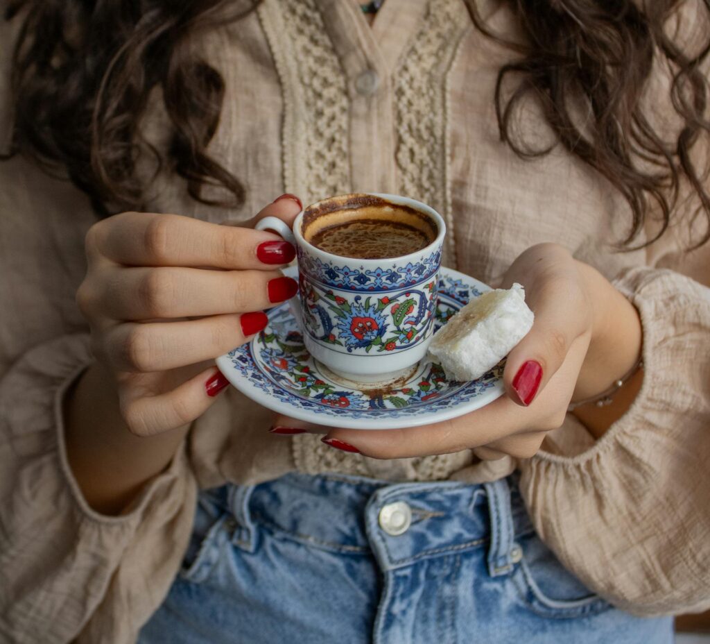 Close-up of a woman holding Turkish coffee and Turkish delight in a traditional setting.