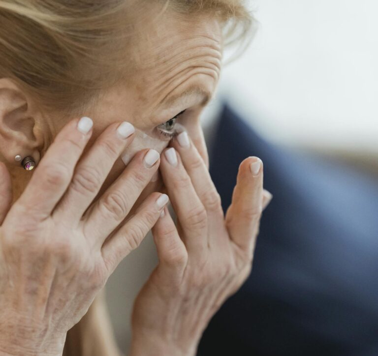 A senior woman applies skincare cream at home, focusing on hydration and anti-aging routine.