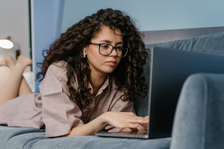 Young woman working on her laptop in a relaxed home setting, focused and comfortable.